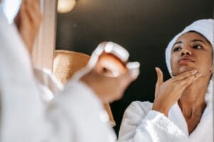 Black woman looking at her skin in a mirror during a skincare routine